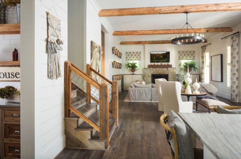 The open living space features all-neutrals, a dark floor and wooden beams on the ceiling plus a matching staircase