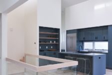 04 The kitchen is done minimal, with grey cabinets, with built-in shelves and a glass railing