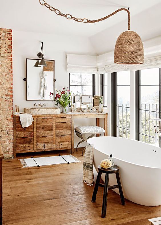 a Californian bathroom with a woven lampshade on a rope, a woodenvanity and a wooden floor