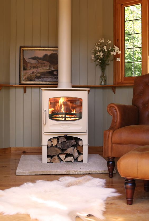 a white wood burning stove is an elegant idea, firewood under it is a cool idea to store it