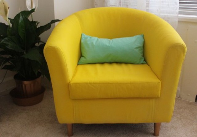 an IKEA Tullsta chair painted in bold yellow using fabric paint and with a mint pillow for a brighter look