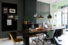 05 A large dining space is done with a black fireplace, a gallery wall, mismatching chairs, a black wooden table and pendant lamps