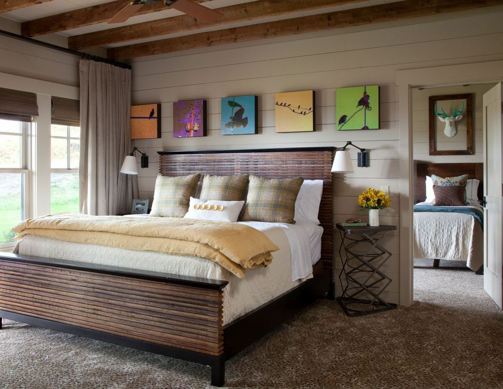 The bedroom is done with a wood slate bed, colorful artworks, metal side tables