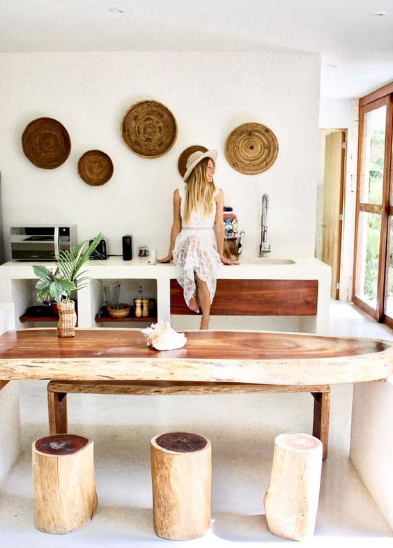 A surf shaped console table, tree stumps as stools and woven plates on the wall