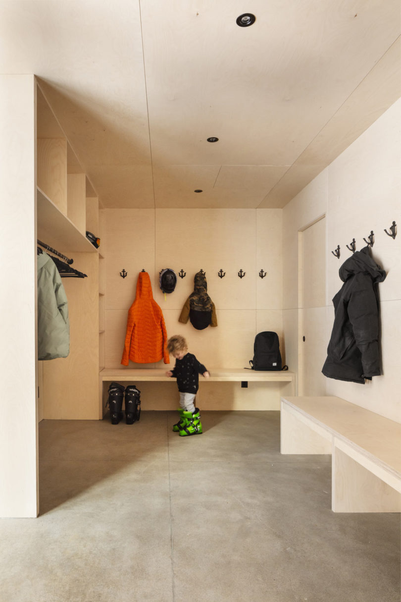 The mudroom is clad with light colored plywood, all the furniture is made of the same plywood