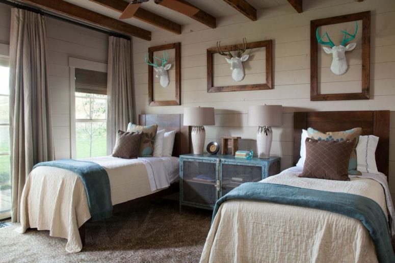 This guest bedroom is done with a blue credenza with sheer doors, catchy fake deer heads and matching beds