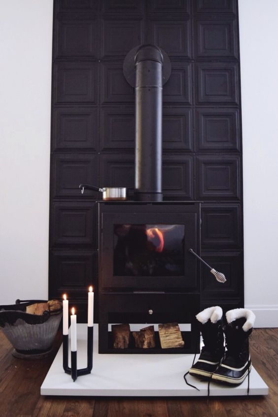 A black modern stove with a black panel wall behind it and a modern candelabra for a bold look