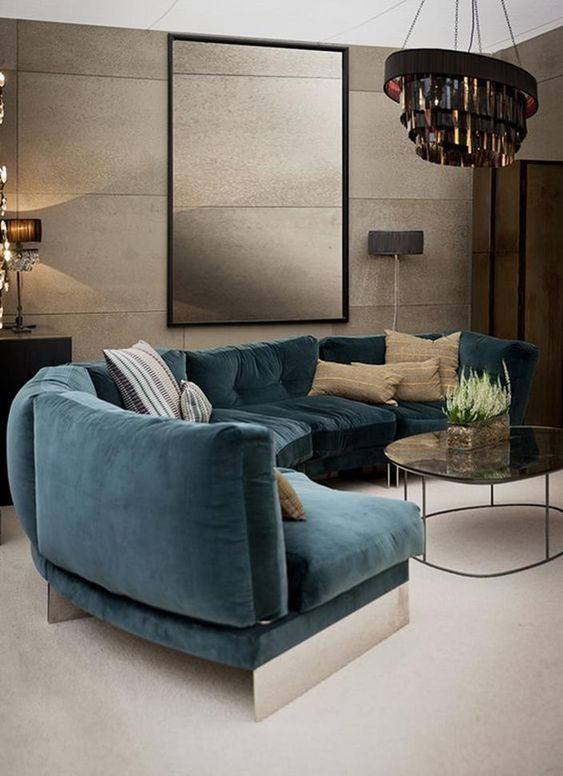 a moody refined living room with a curved teal sofa that adds color to the space and makes it bolder