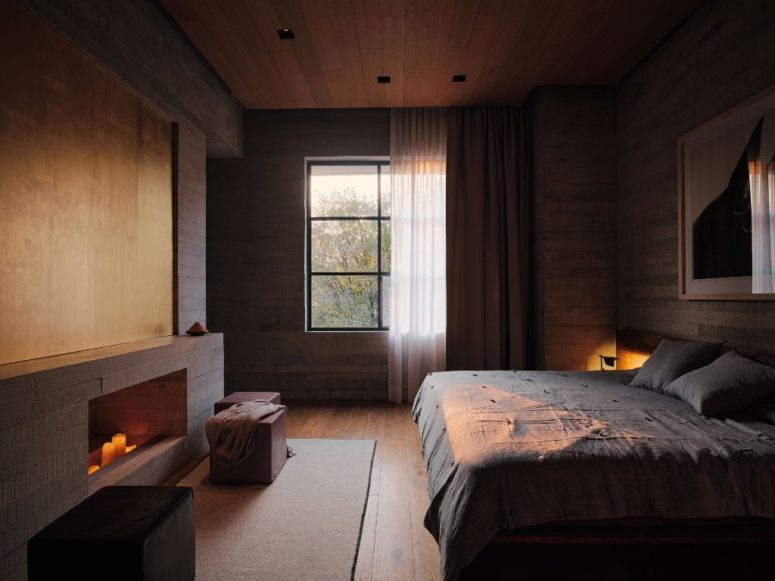 This bedroom features lots of wood, a large bed and a window, a non-working fireplace with candles