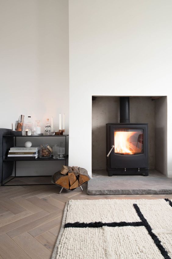 a minimalist space with a white sleek niche with a small modern wood burning stove is a cool idea
