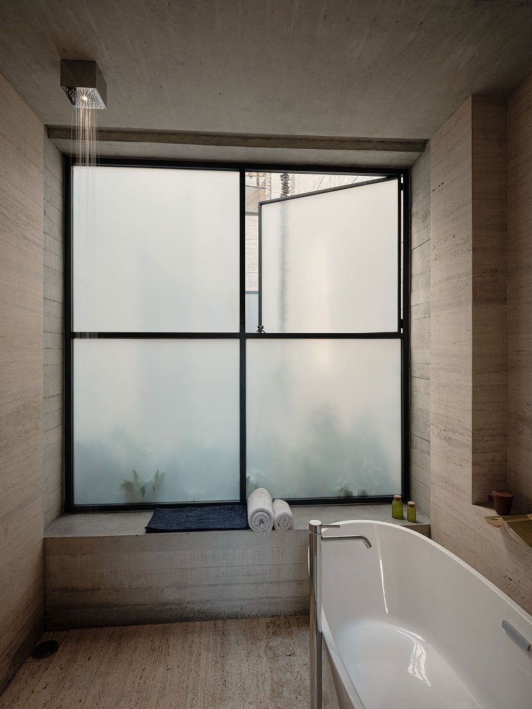 The bathroom is done with a frosted glass window, an oval tub and simple yet luxurious items