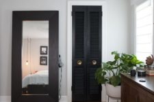 17 a black shutter door to the closet echoes with a dark wooden frame of the mirror and a printed rug