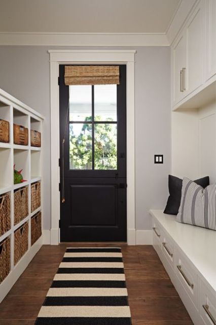 a black door echoes with a striped rug and throws of the mudroom adding a chic and bold touch to the space