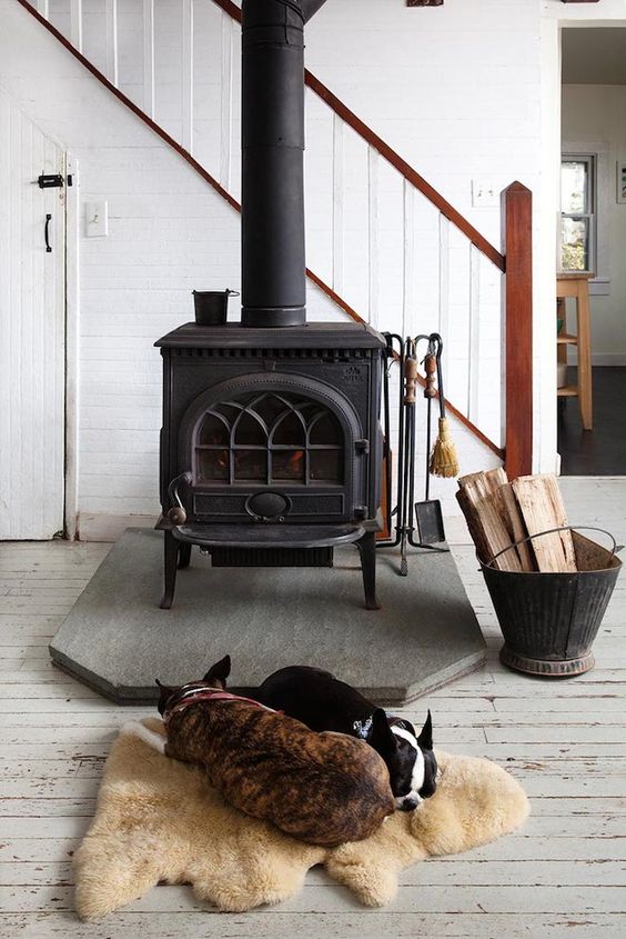A modern farmhouse space with a vintage black wood burning stove and a cozy rug next to it