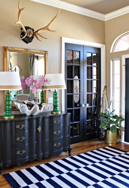 black French doors, a black sideboard and a navy and white striped rug create a cohesive look in the space