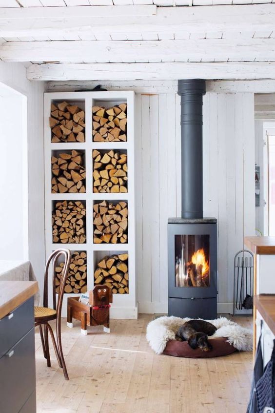 a Scandinavian space with a modern and cool wood burning stove plus an elegant open storage unit for firewood