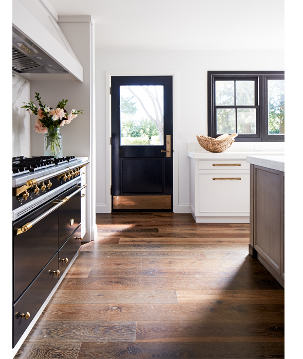 a chic kitchen with a touch of art deco - a black and gold cooker and a matching door and black frame windows
