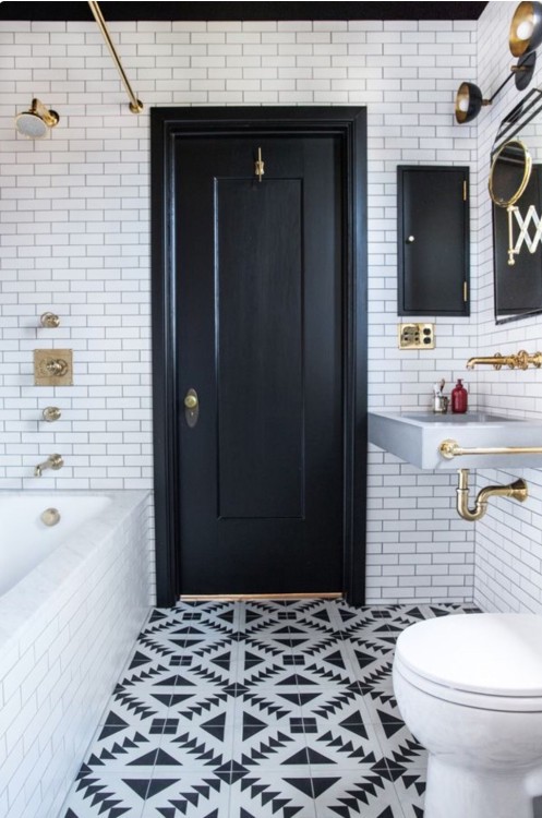 a chic monochromatic bathroom with patterned tiles, a black door and a ceiling for a bold look