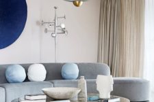 22 a neutral living room made bold with a curved grey sofa, a navy artwork and a marble coffee table and a cork stool