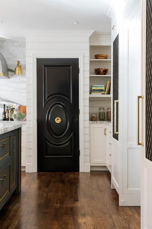 a chic black door echoes with the kitchen island done in the same color creating a bold and chic look