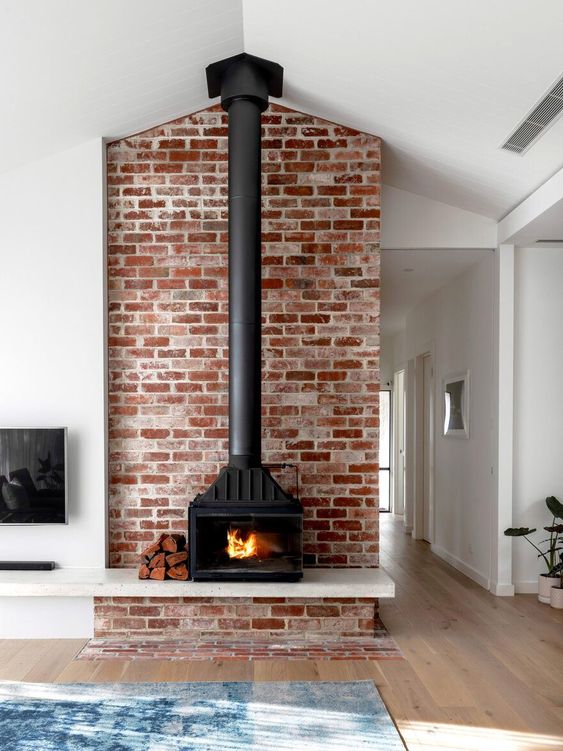 a wood burning stove placed in front of a brick wall to make it more safe and highlight it as much as possible