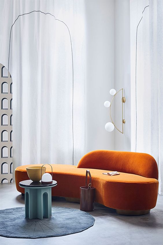 a  bold conceptual living room with a curved orange sofa, a round blue rug and a turquoise table for a bold setup