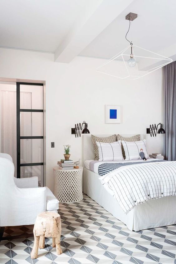 a statement geometric chandelier is paired with wall sconces and make the bedroom more welcoming
