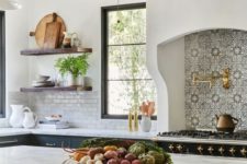 a Spanish kitchen with a large cooker, a printed backsplash, gold touches, dark furniture and lamps with a vintage feel