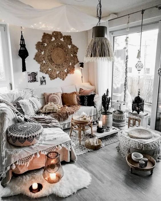 a boho Moroccan living room in neutrals, with a macrame rug, ottomans and throws, candle lanterns and lights