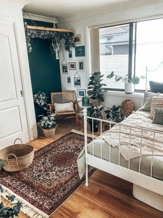 a boho bedroom with a Persian rug, a dark green accent wall, a gallery wall, some crochet bedding