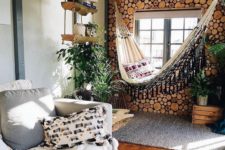 a boho space with a neutral color palette, a wood slice wall, a hammock, layered rugs and lots of greenery