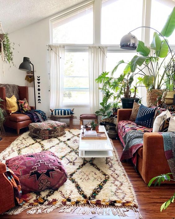 a bright boho space with printed rugs and throws, potted greenery and cool floor lamps and cushions