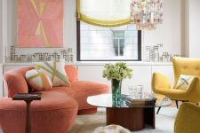 a bright living room with a coral curved sofa, yellow chairs, a pastel rug, a coffee table and a bright chandelier