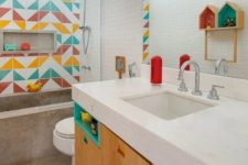a bright modern kids’ bathroom with a colorful tile wall, bright niches and a concrete bathroom is a fresh idea