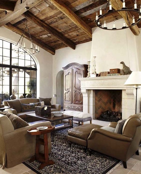 a chic Spanish living room with white plaster walls, reclaimed wood ceiling with beams, neutral furniture and vintage chandeliers