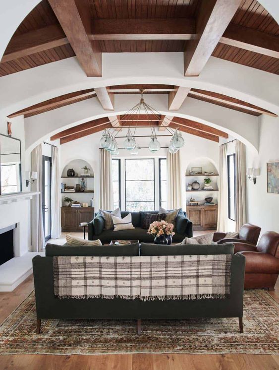 a chic Spanish living room with white walls and ceilings, wooden beams, dark furniture and a catchy chandelier