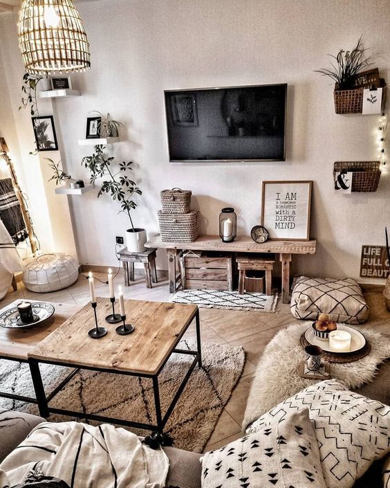 a chic neutral boho room with wooden furniture, lots of potte greenery, various prints and touches of black
