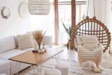 a clear white boho room with a round rattan chair, a wicker lampshade, boho rugs and faux fur plus natural wood