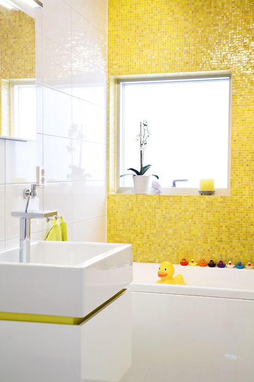 a colorful and fun kids' bathroom in bright yellow and white, some bright accessories and colorful ducks