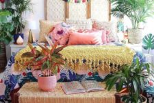 a colorful boho bedroom with all bright textiles and linens, lots of potted plants, a colorful tassel garland and Moroccan lamps