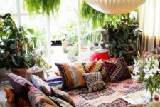 a colorful boho living room with a bright curtain, a sunken seatign area with lots of throws and blankets