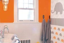 a colorful kids’ bathroom in grey, orange and white, with an oversized elephant artwork, grey stools, vintage lamps