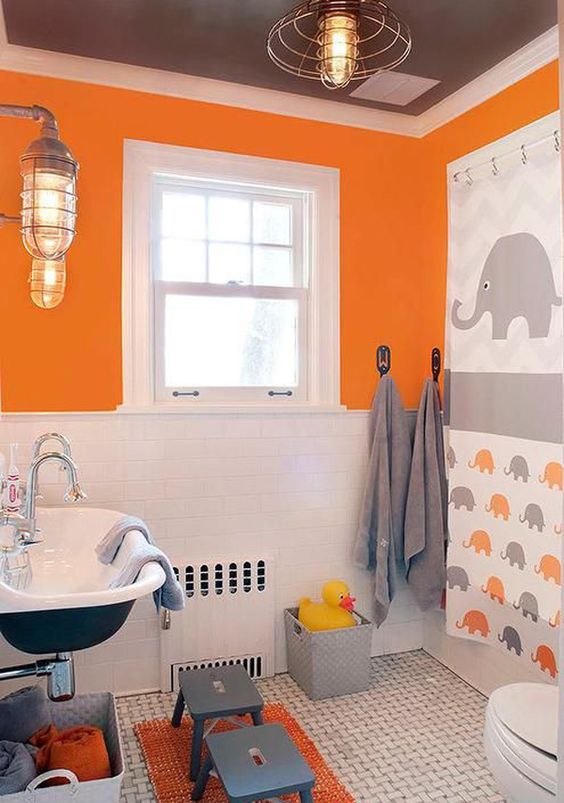 a colorful kids' bathroom in grey, orange and white, with an oversized elephant artwork, grey stools, vintage lamps