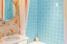 a colorful kids’ bathroom in light blue and orange, with a seascape theme, bright tiles and vintage-inspired wallpaper
