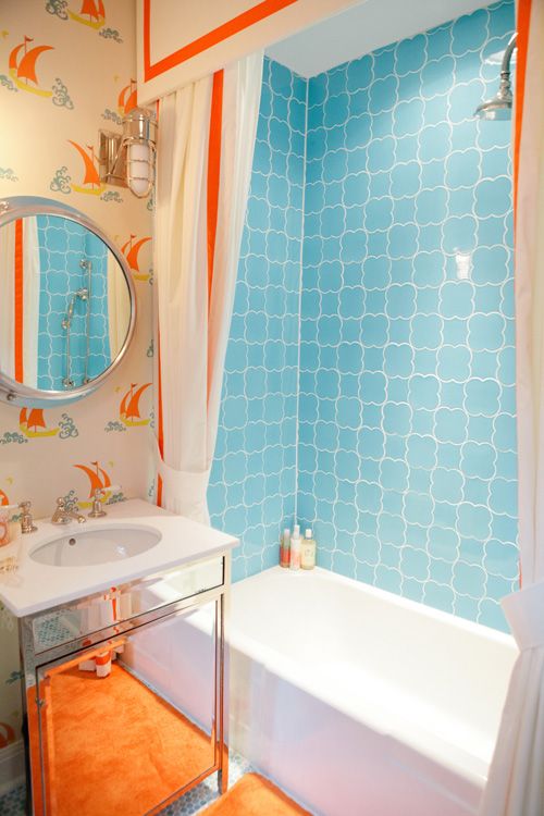A colorful kids' bathroom in light blue and orange, with a seascape theme, bright tiles and vintage inspired wallpaper