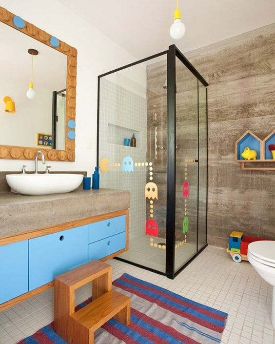 a contemporary kids' bathroom with a colorful vanity, bright shelves, a colorful rug, colorful decals on the shower