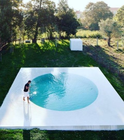 A cool minimalist round pool with a white frame around looks very eye catching and allows relaxing on this watery deck, too