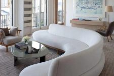 a curved white couch makes a stylish statement in the living room and it also separates the zones of the space
