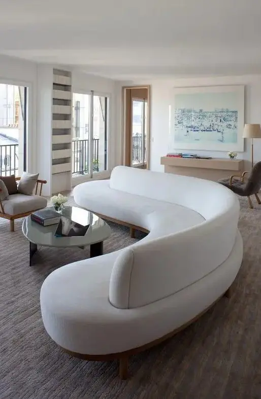 a gorgeous curved white sofa takes over the whole living room and adds soft lines and shapes to it