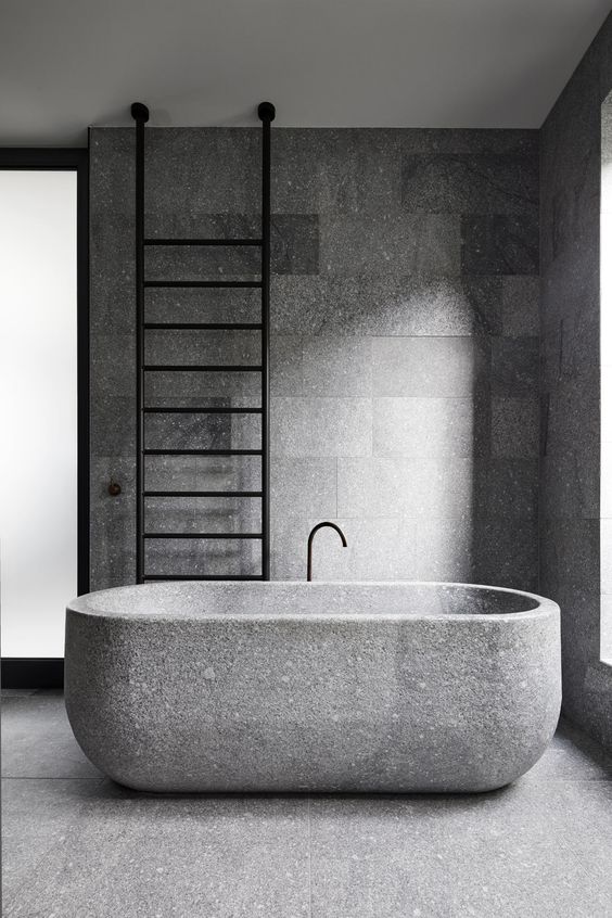 a minimalist granite bathroom with a granite bathtub plus a black ladder is a cool idea for an edgy feel
